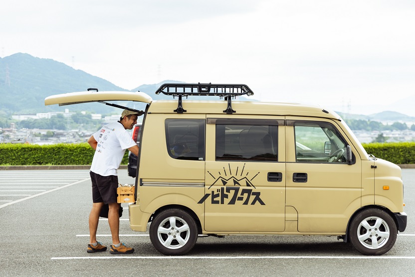 『ノビトワークス』のロゴが入った自動車と原田さん